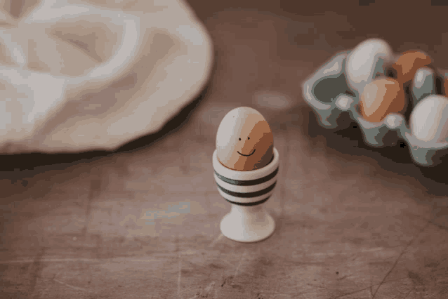 an egg with a face drawn on it is in a striped cup