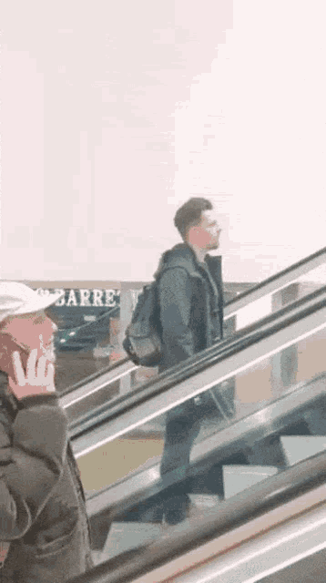 a man talking on a cell phone while walking down an escalator