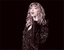 taylor swift is singing into a microphone in a black and white photo .