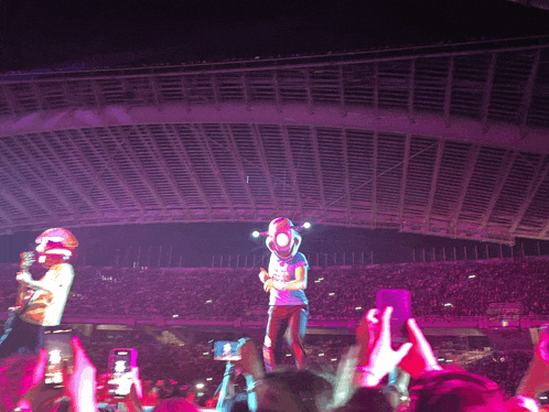 a man in a cowboy hat sings into a microphone in front of a crowd at a concert