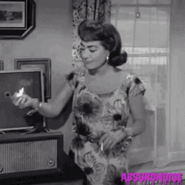 a woman in a floral dress is holding a lighter in her hand and dancing in a living room .