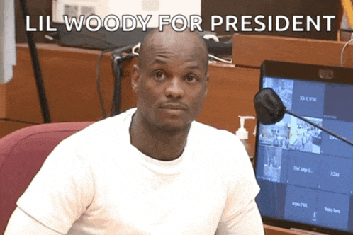 a man sitting in front of a monitor with the words lil woody for president written on it