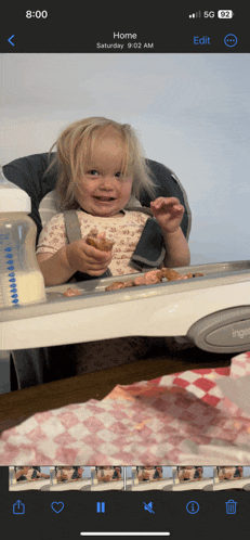 a phone screen shows a little girl eating food and the time is 8:02