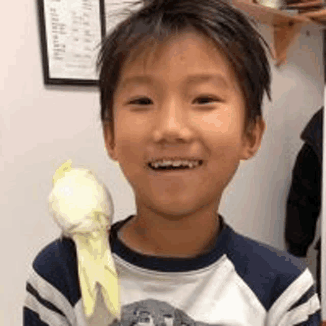 a young boy is holding a parrot in his hand and smiling for the camera .