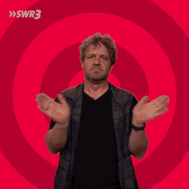 a man with his arms outstretched in front of a pink background with swr3 in white letters