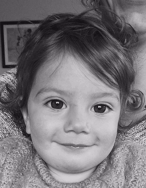 a black and white photo of a little girl 's face