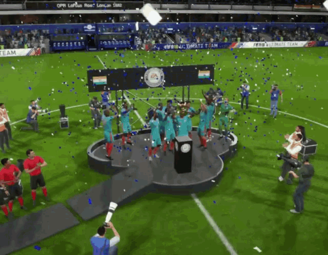 a group of soccer players are celebrating on a stage with a trophy in front of a sign that says fifa ultimate team