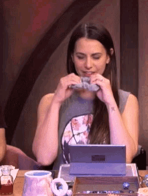 a woman with a tattoo on her wrist is eating a piece of food