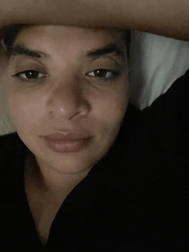 a close up of a woman laying in bed with her hand on her head