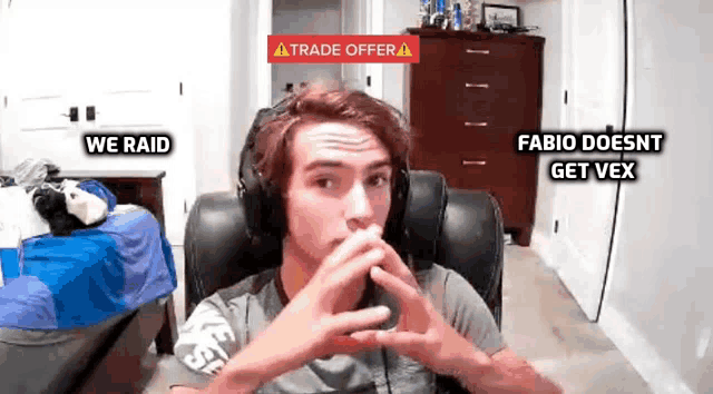 a man wearing headphones is sitting in front of a screen with a trade offer sign above him .