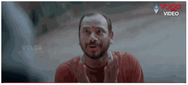 a man with a beard and a red shirt is making a funny face in a movie .