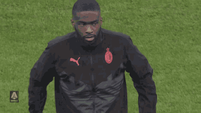 a man in a black jacket with a red puma logo