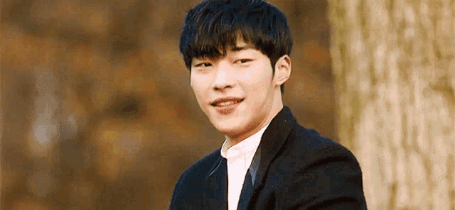 a young man in a suit and tie is smiling for the camera .