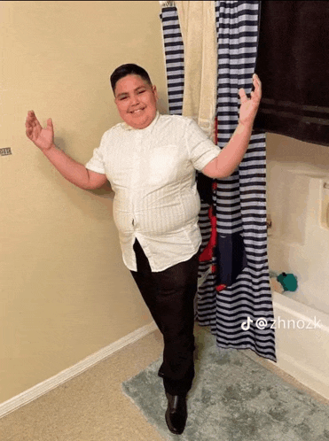 a man in a white shirt and black pants stands in a bathroom