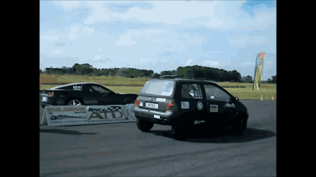 two cars are racing on a track with a sign that says atd on it
