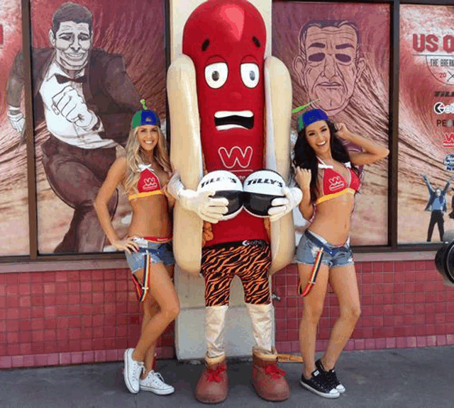 two women standing next to a hot dog mascot with the letter w on his face