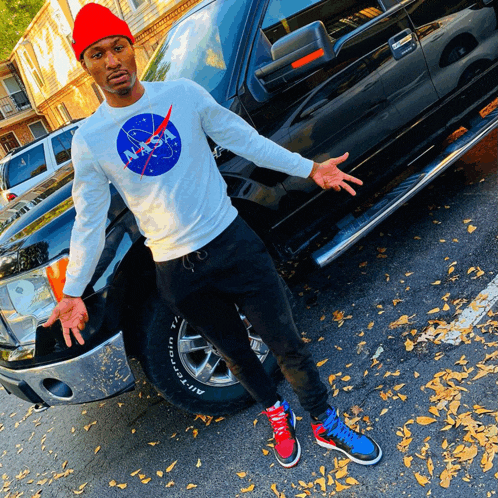 a man wearing a nasa shirt is standing next to a black truck