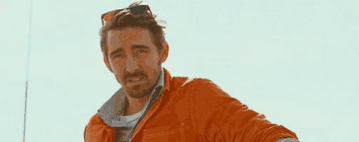 a man wearing sunglasses and an orange jacket is smiling .