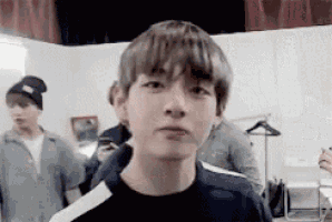 a young man in a black shirt is making a funny face while standing in a room .