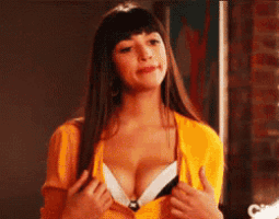 a woman in a yellow sweater is taking off her bra and smiling .