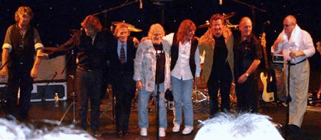 a group of people standing on a stage with a drum set