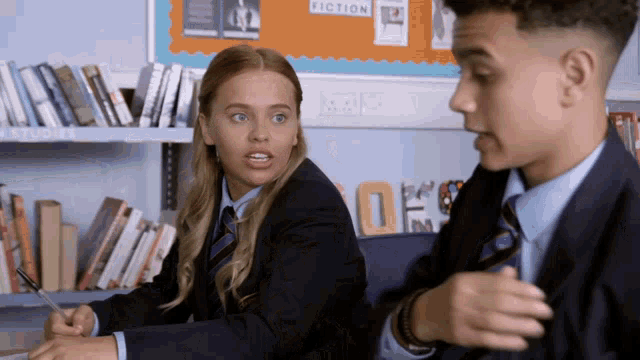 a boy and a girl are sitting in front of a bulletin board that has the word fiction on it