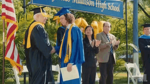 a man in a graduation cap and gown stands in front of a sign that says madison high school on it