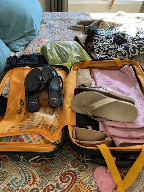 a suitcase filled with clothes and flip flops with the word you on the side