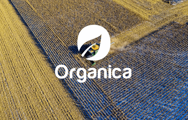 an aerial view of a tractor plowing a field with the organica logo behind it