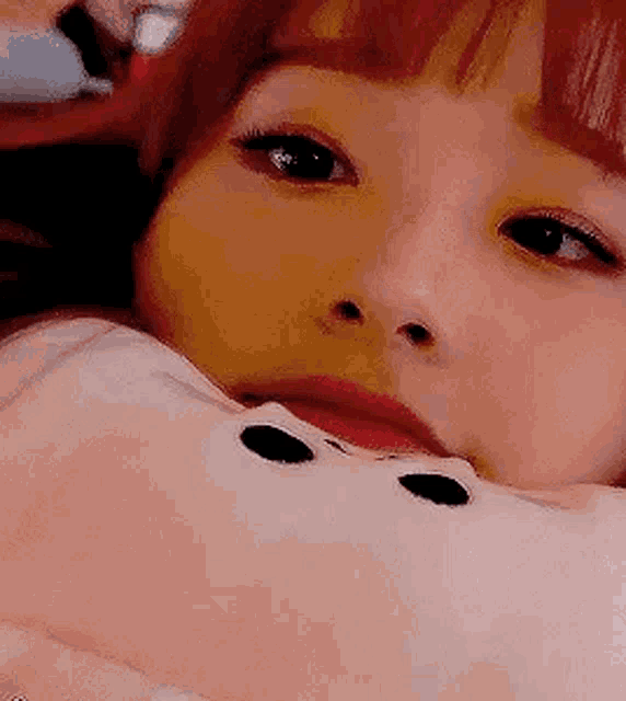 a close up of a woman laying on a bed with a stuffed animal in her mouth .