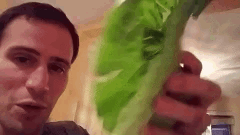 a man is holding a large piece of green lettuce in his hands .