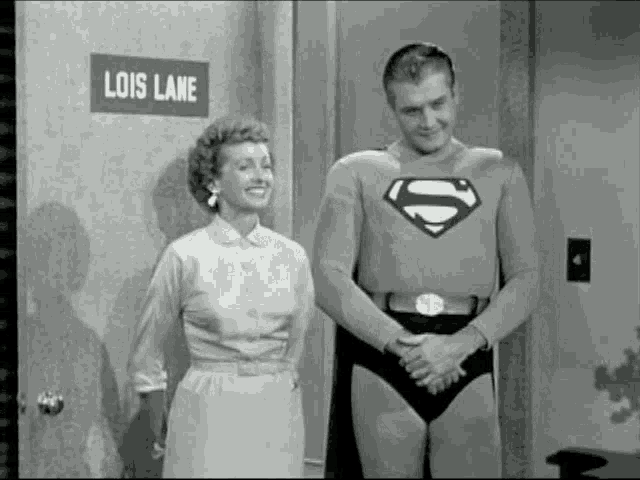 a man in a superman costume is standing next to a woman in front of a door that says lois lane .
