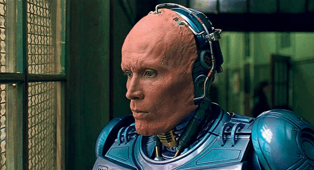 a robot with a bald head and headphones looks out of a window