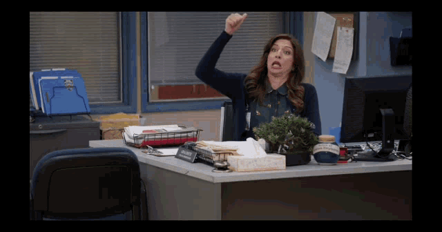 a woman sitting at a desk with a bonsai tree in front of her and a name tag that says ' detective '