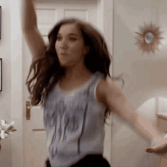 a woman in a tank top is dancing in a living room .