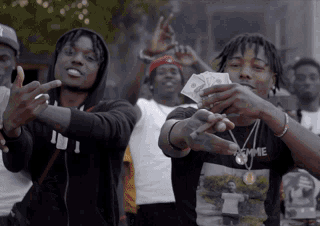 a man wearing a black shirt that says lemme holds a bunch of money