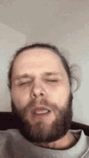 a man with a beard and long hair is making a funny face