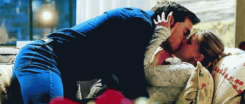 a man and a woman are kissing on a couch in front of a window .