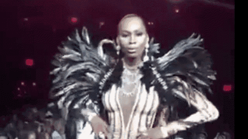 a woman is standing on a stage wearing a feathered outfit .
