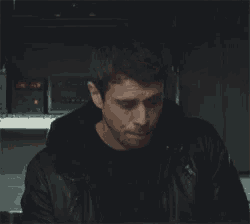 a man in a black jacket is looking at a computer screen