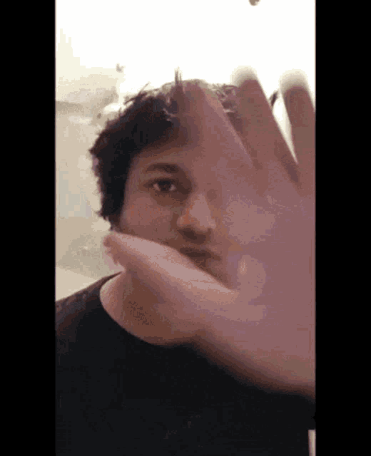 a man covering his face with his hand in a blurry photo