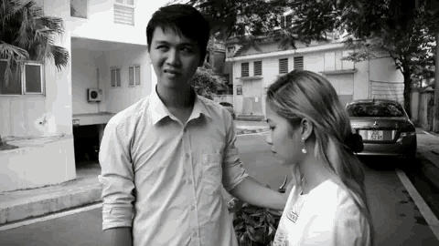 a black and white photo of a man and a woman standing next to each other with a license plate that says aeh