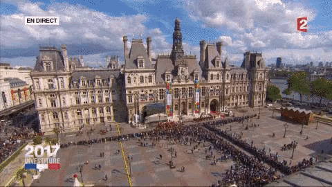 a large crowd of people are gathered in front of a large building with the year 2017 on the screen