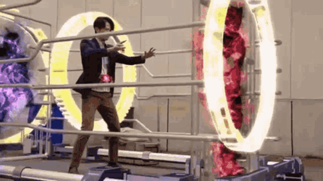 a man in a suit is standing in front of a machine that looks like a ring of fire .