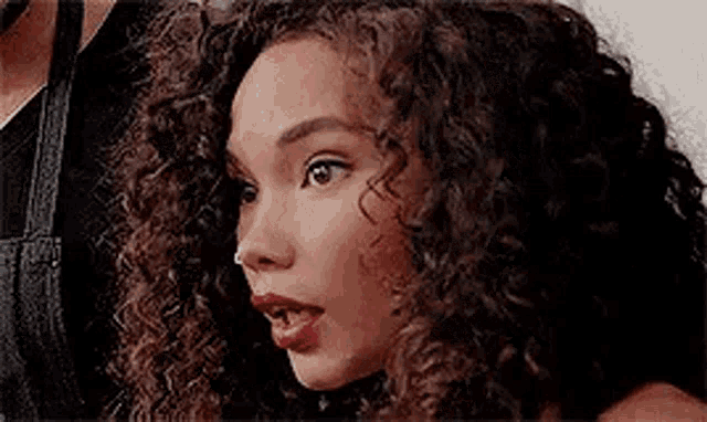 a close up of a woman 's face with curly hair and red lipstick .