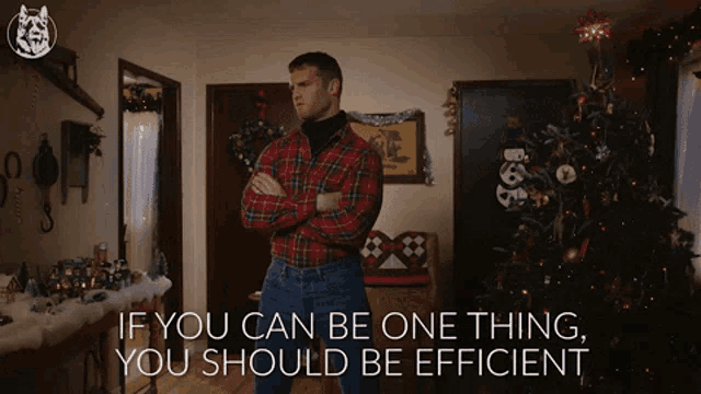 a man in a plaid shirt is standing in front of a christmas tree with the words if you can be one thing you should be efficient