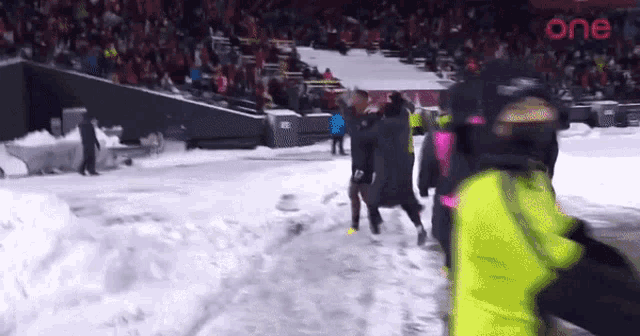 a group of people are walking through the snow in front of a crowd .