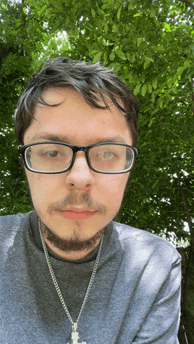 a young man wearing glasses and a cross necklace