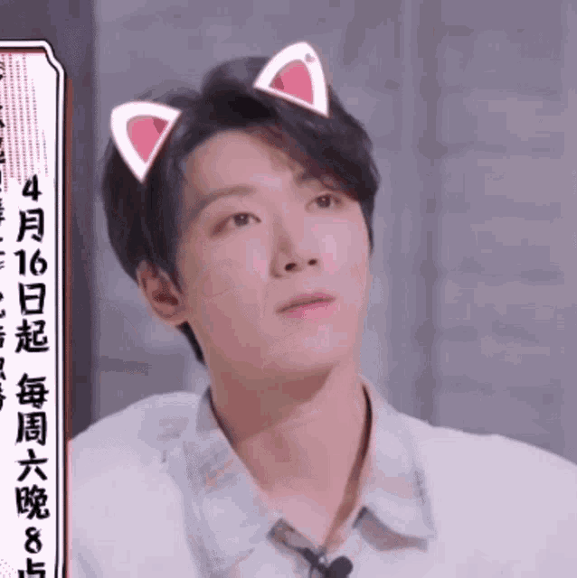 a young man with cat ears on his head looks up at something