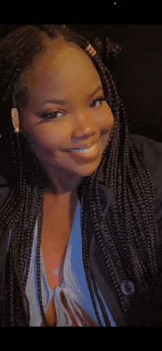 a woman with braids is smiling and wearing a blue top